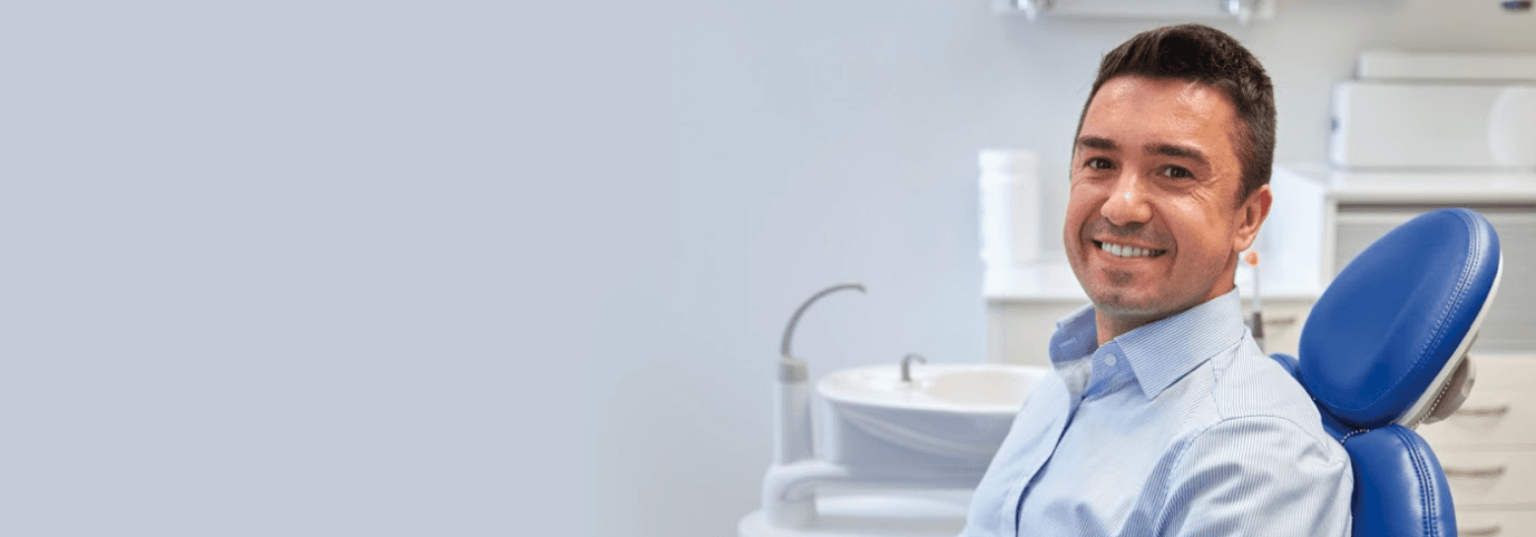 Male in a blue dental chair smiles after root canal therapy in Chesterfield